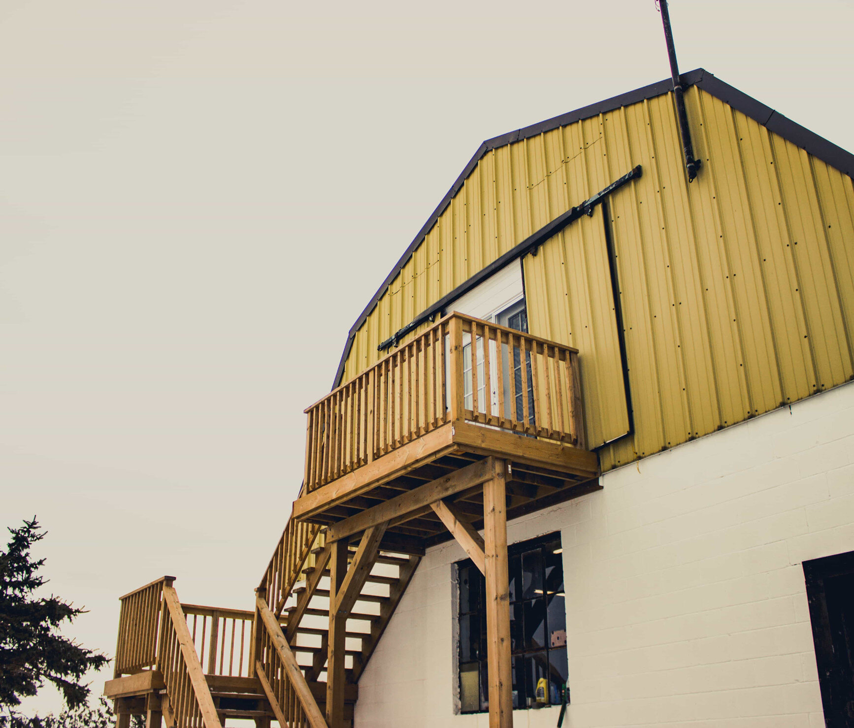 A view of the side of a barn with a wooden staircase leading to the upper level